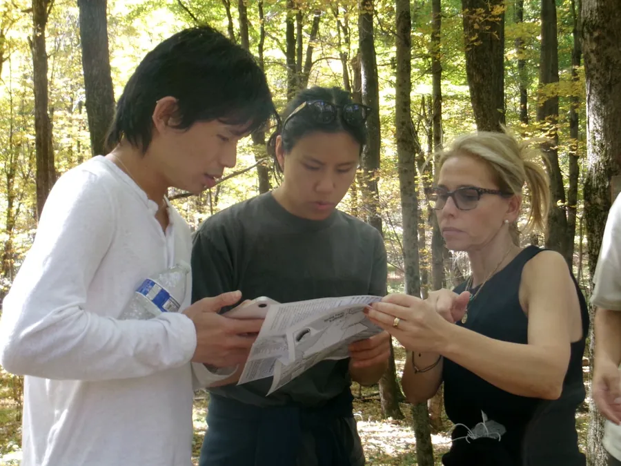 Teammates reading a trail map together in the woods